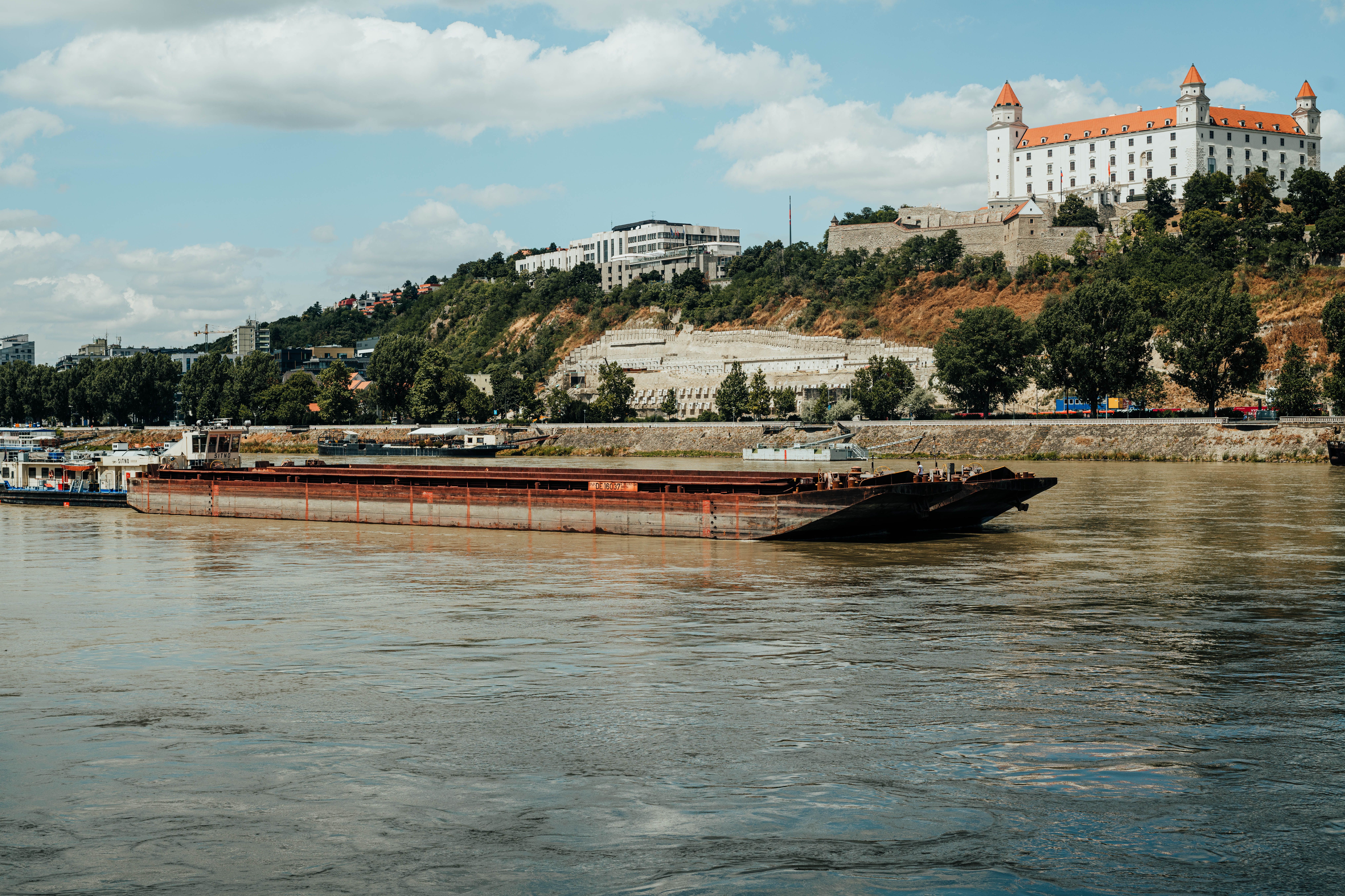 ברטיסלבה: A picturesque barge cruising the Danube river with Bratislava Castle in the background.
