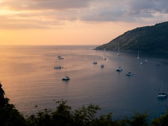 פוקט: Tranquil view of sailboats and yachts in Phuket, Thailand with a warm sunset horizon.