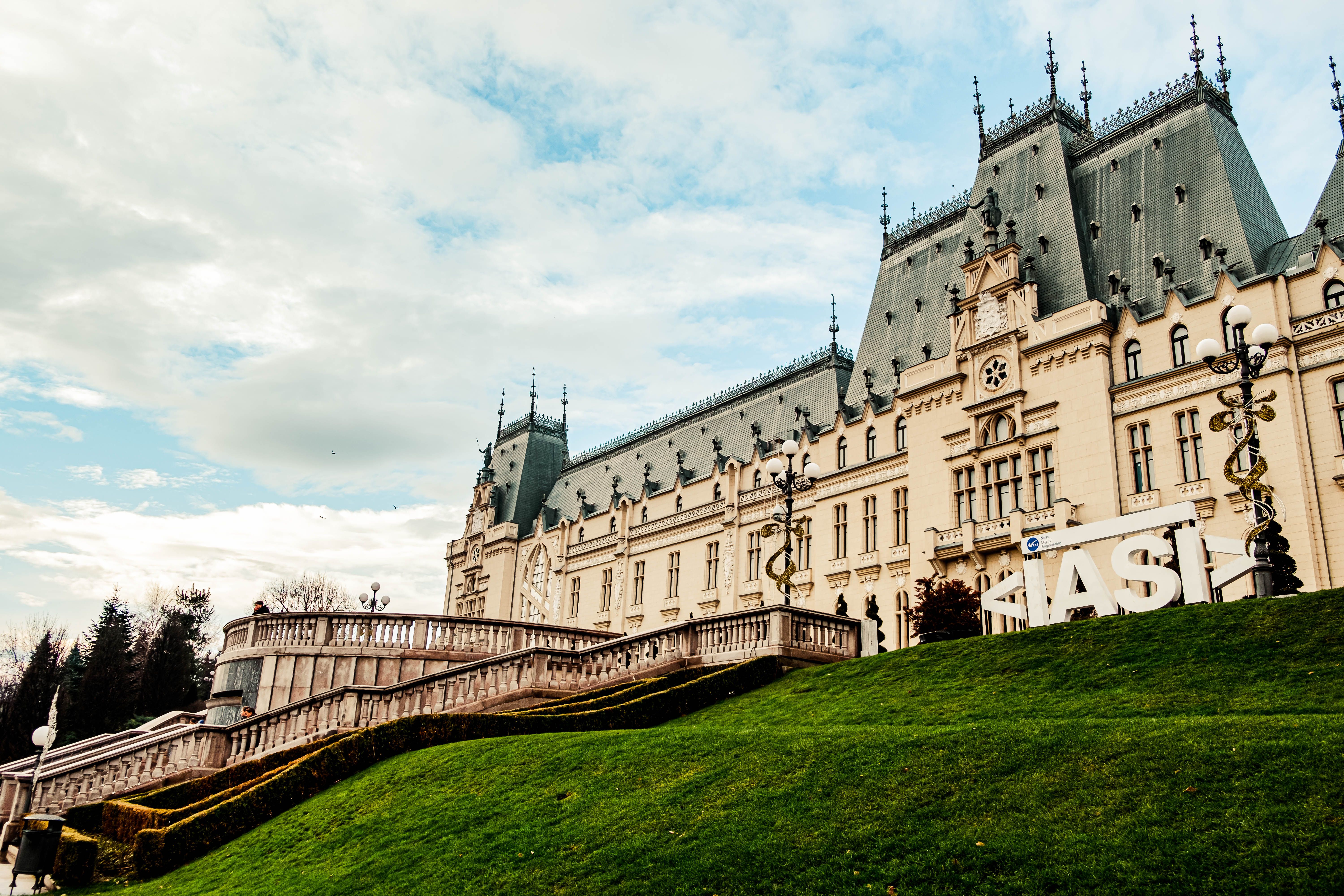 יאשי: Majestic Gothic Revival Palace of Culture in Iasi, Romania with green lawns and cloudy skies.