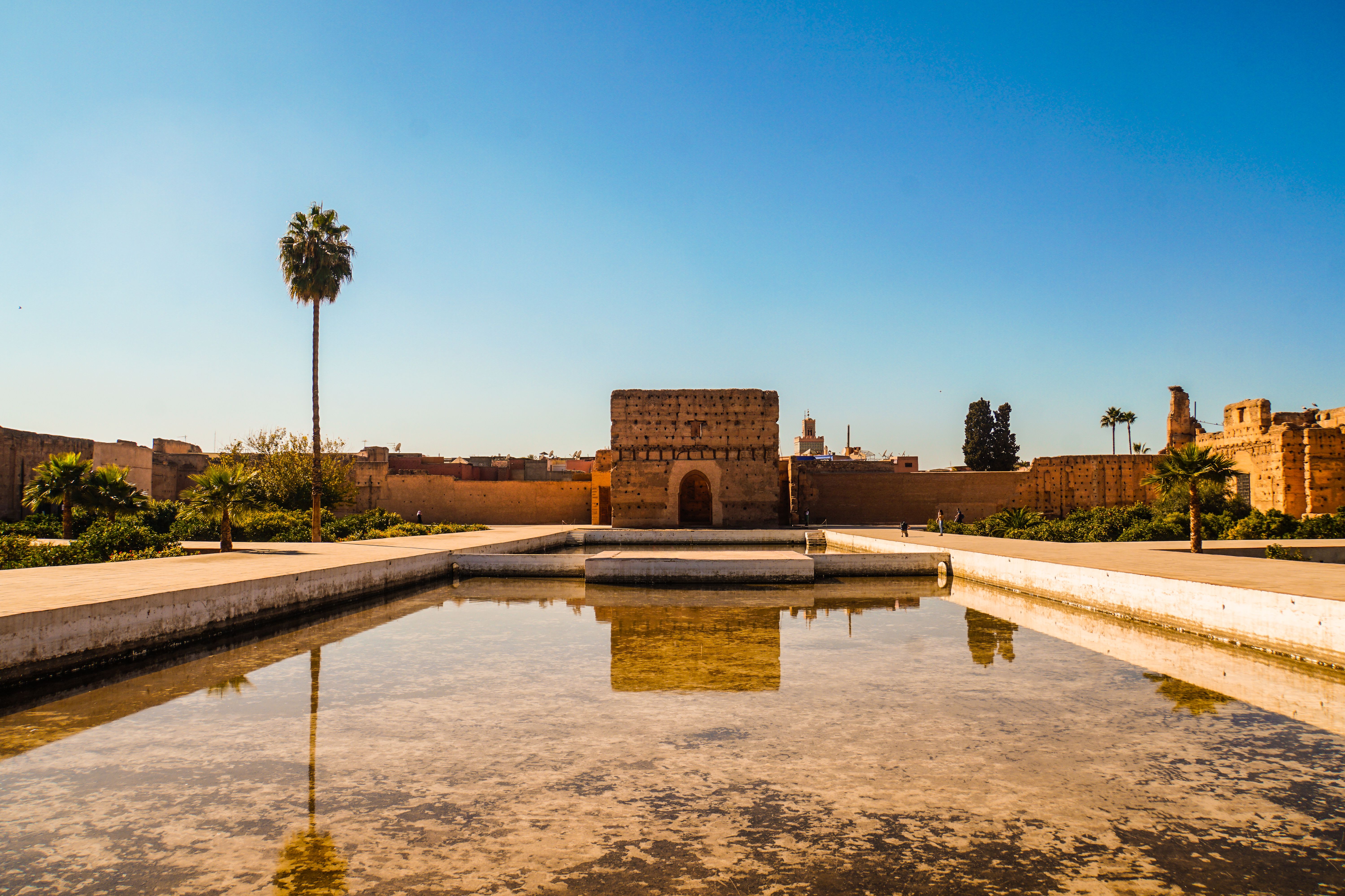 מרקש: El Badi Palace in Marrakech under a clear blue sky with a reflecting pool in the foreground.