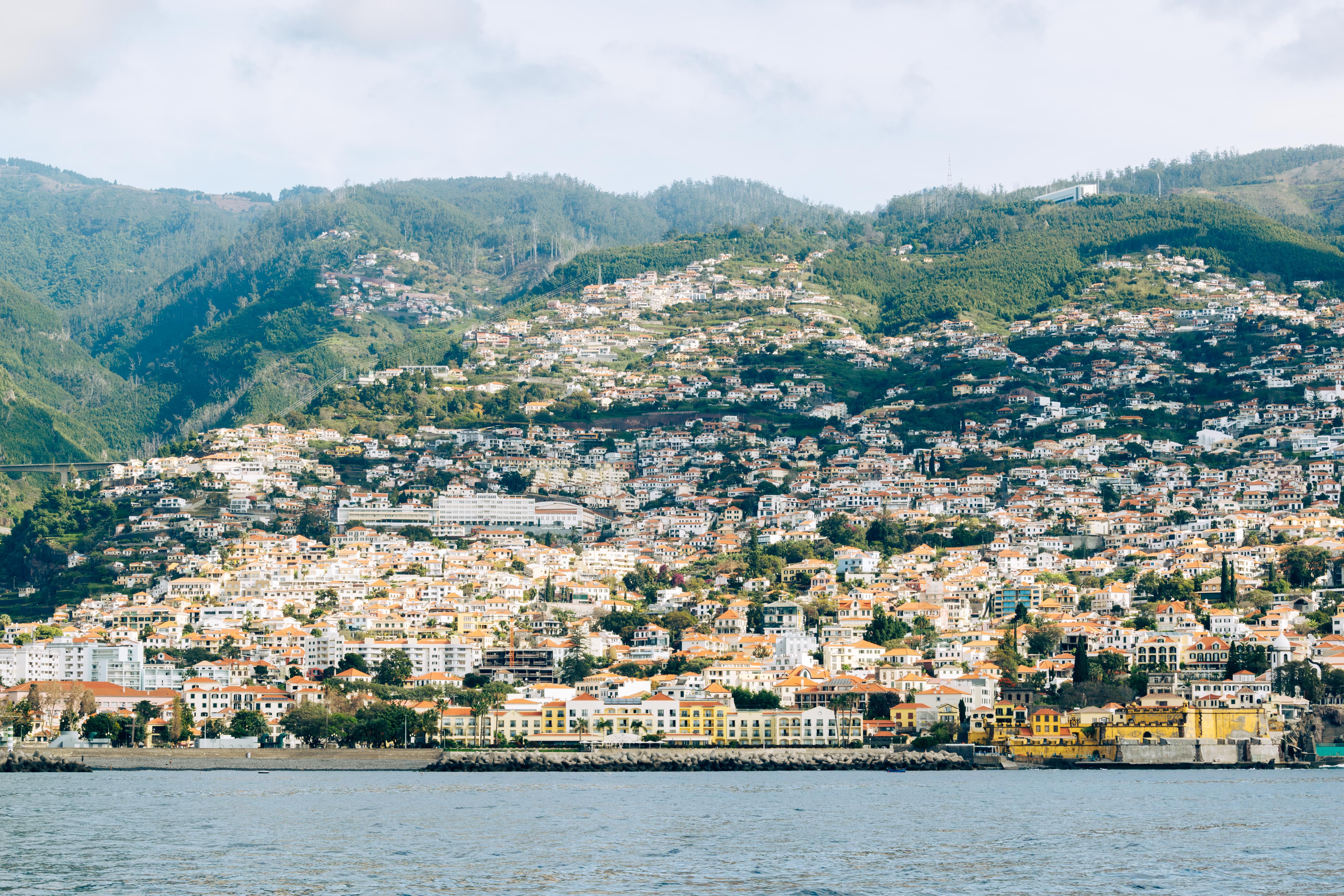 מדיירה: Scenic view of Madeira's hillside urban landscape with vibrant architecture and lush green hills.