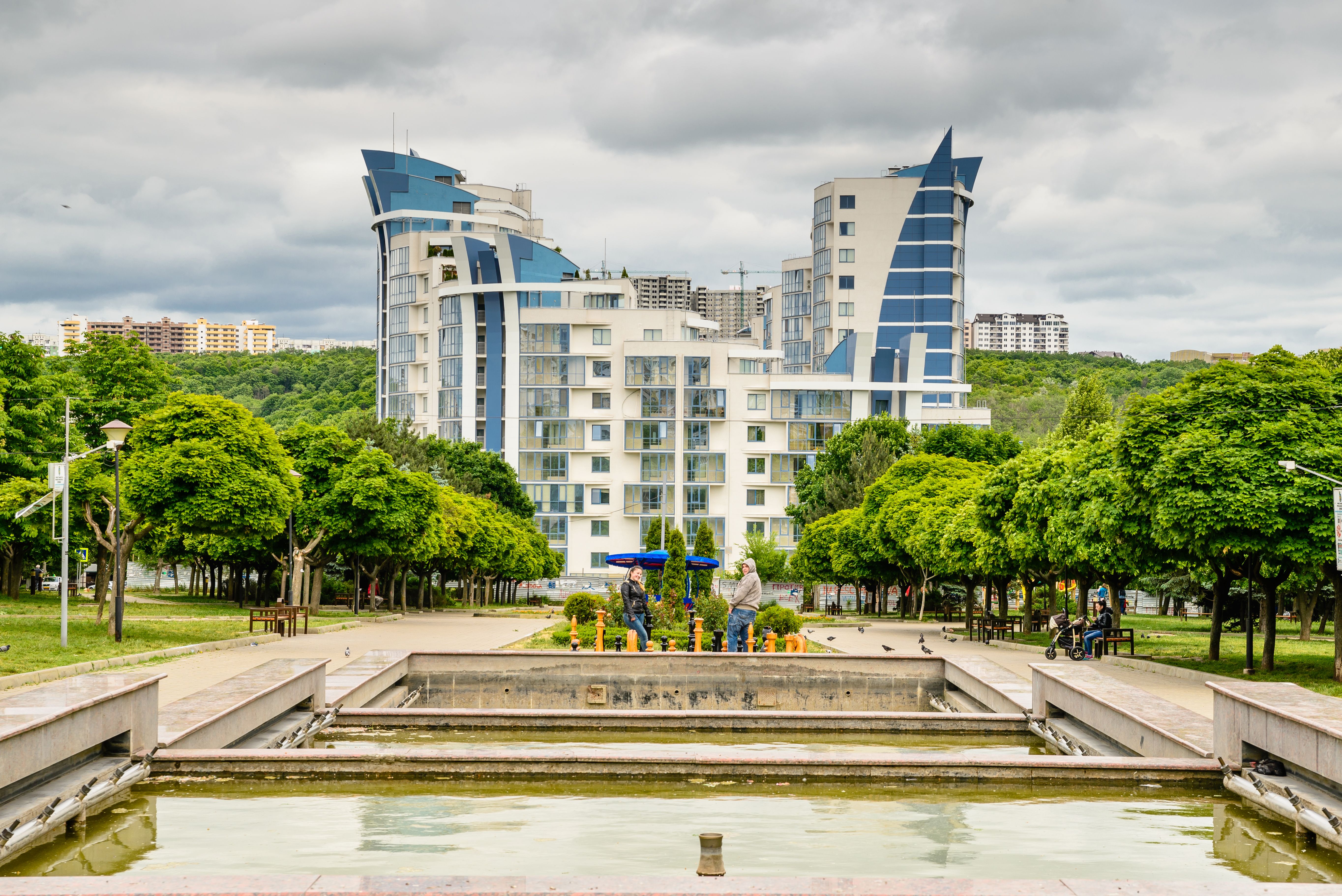 קישינב: Explore modern buildings and lush greenery in a vibrant Chișinău park setting with a serene pond view.