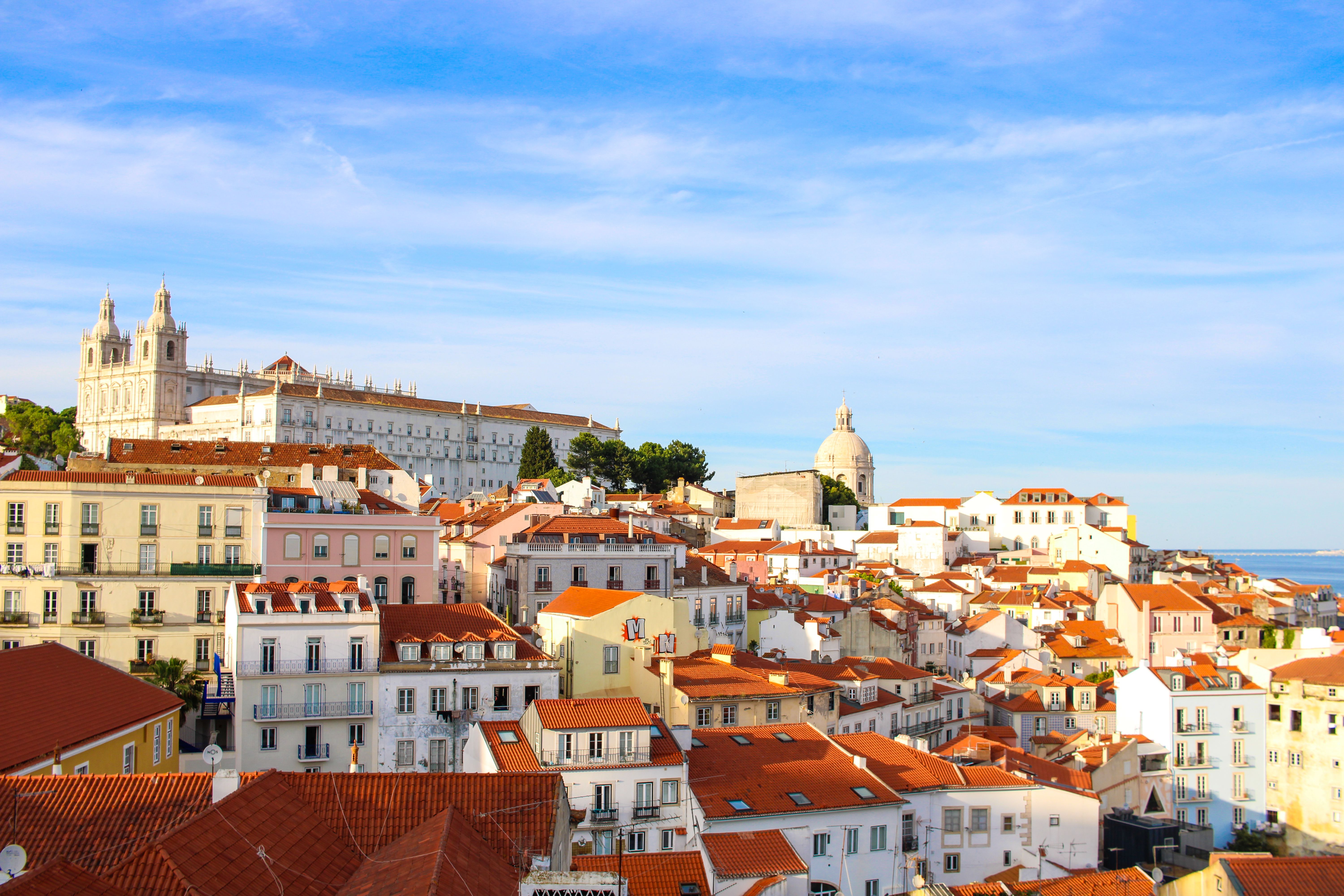 ליסבון: A scenic view over Lisbon's historic Alfama district showcasing traditional architecture under a clear sky.