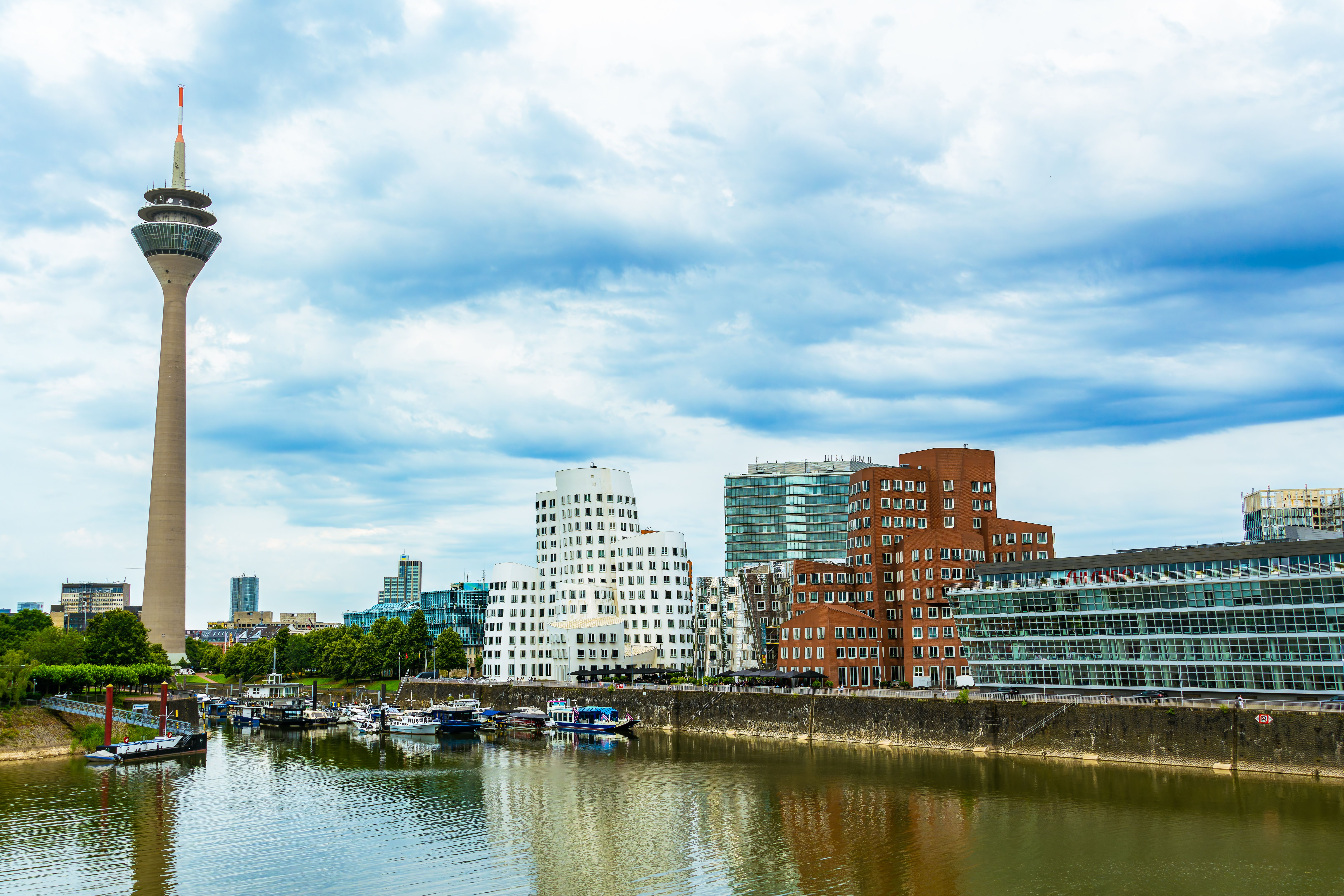דיסלדורף: Skyline view of Düsseldorf featuring modern architecture and Rhine Tower by the river.