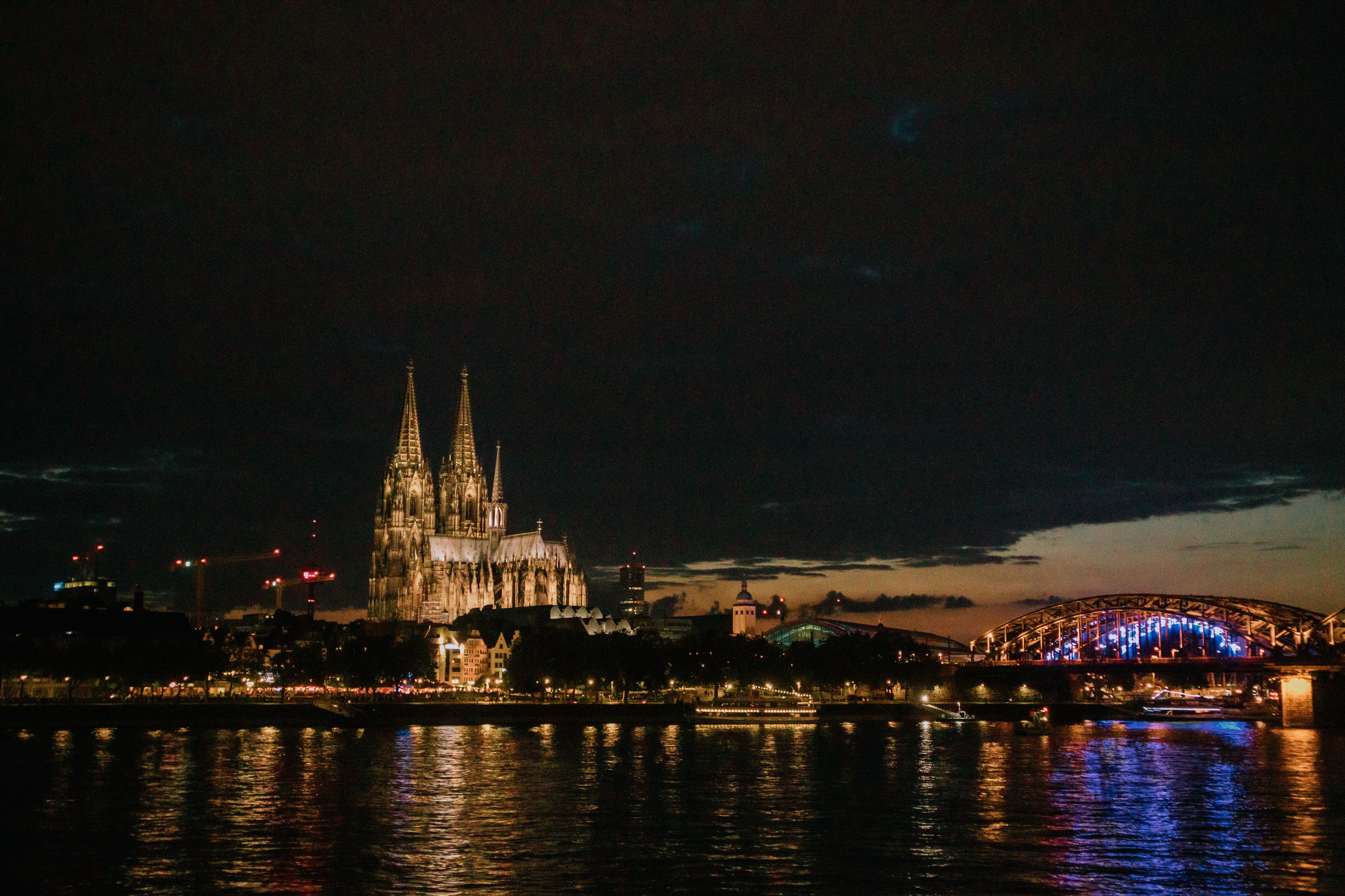קלן: View of Cologne Cathedral and Hohenzollern Bridge illuminated at night, reflecting in the Rhine River