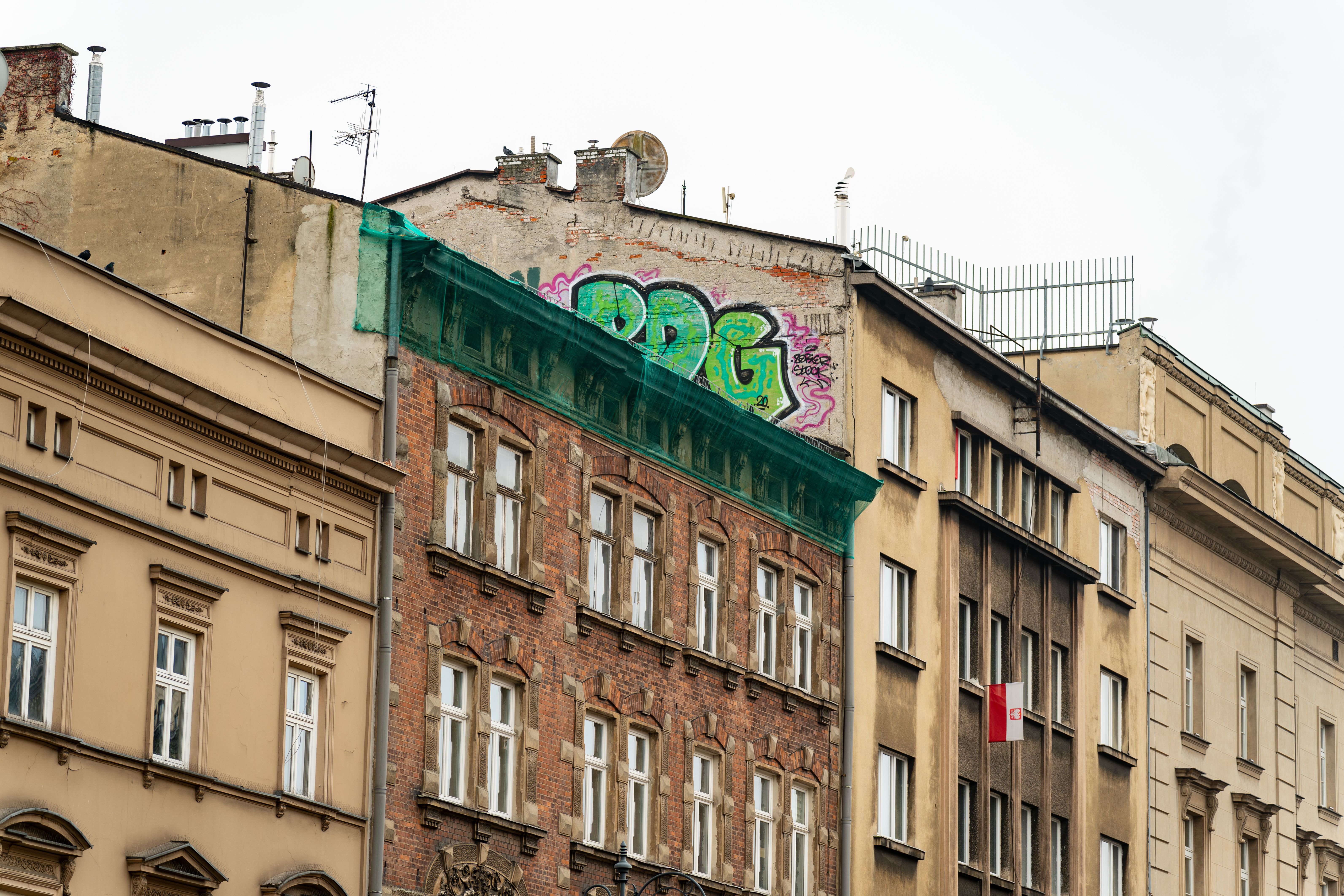 קרקוב: Colorful graffiti on historic buildings in Kraków, Poland, showcasing urban art contrasting old architecture.