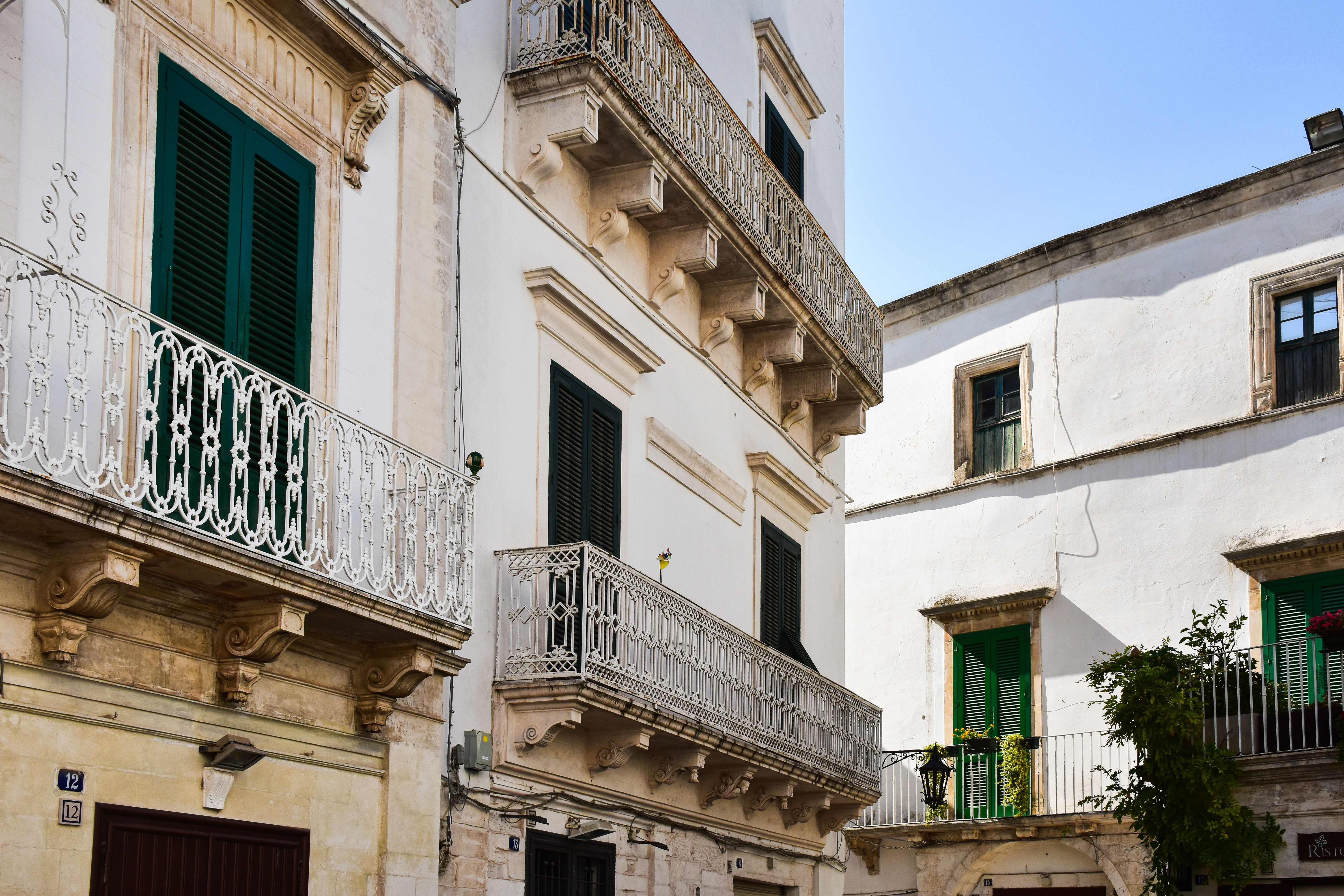 בארי: Charming white buildings with ornate balconies in a sunlit Italian street.