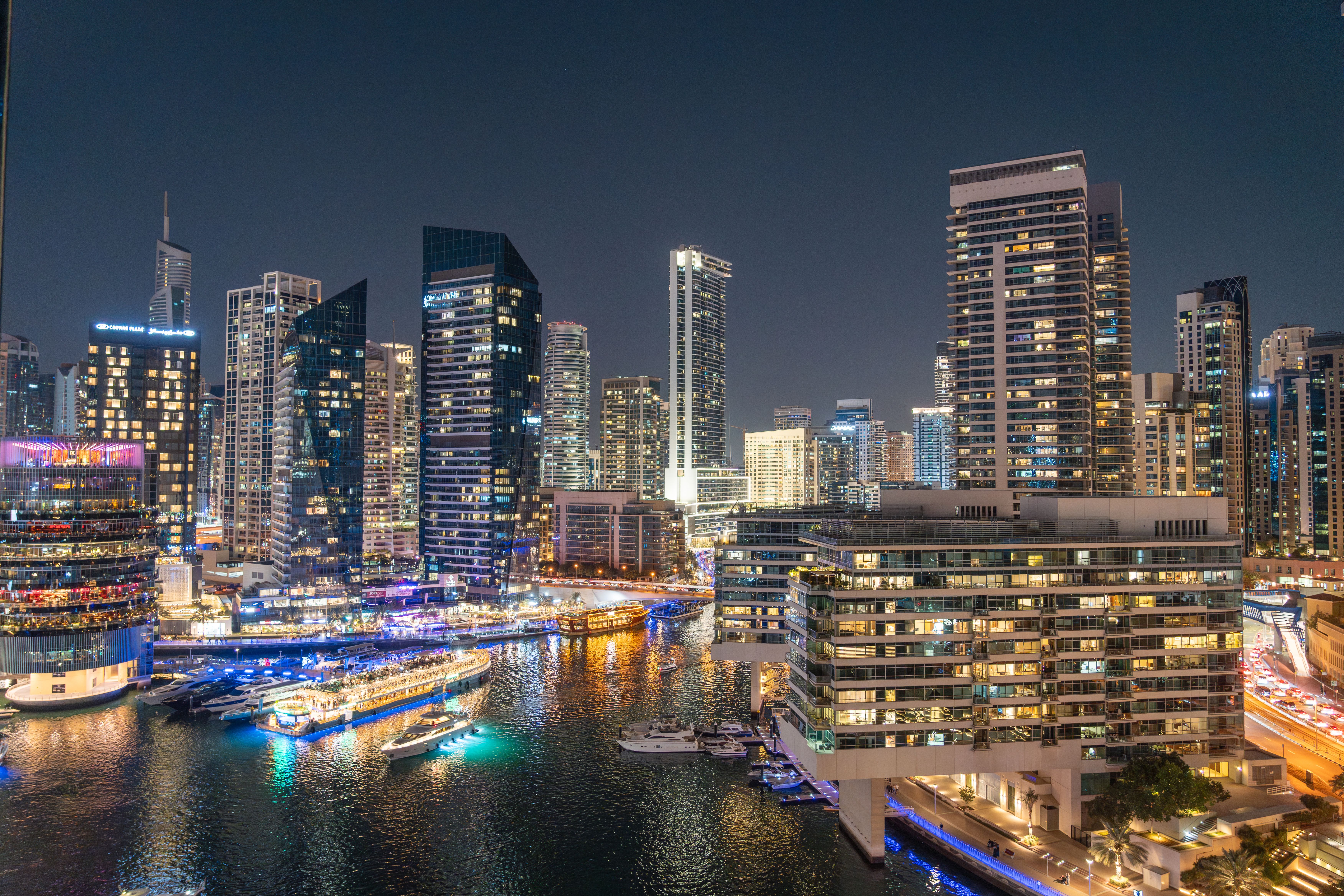 דובאי: Stunning night view of Dubai Marina with illuminated skyscrapers and reflections on the water.