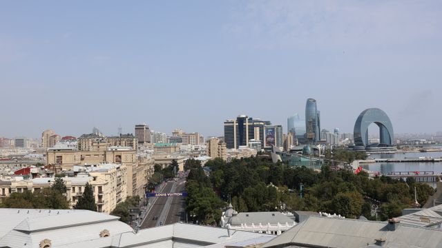 באקו: Aerial view of Baku featuring unique modern architecture and buildings against a clear blue sky.