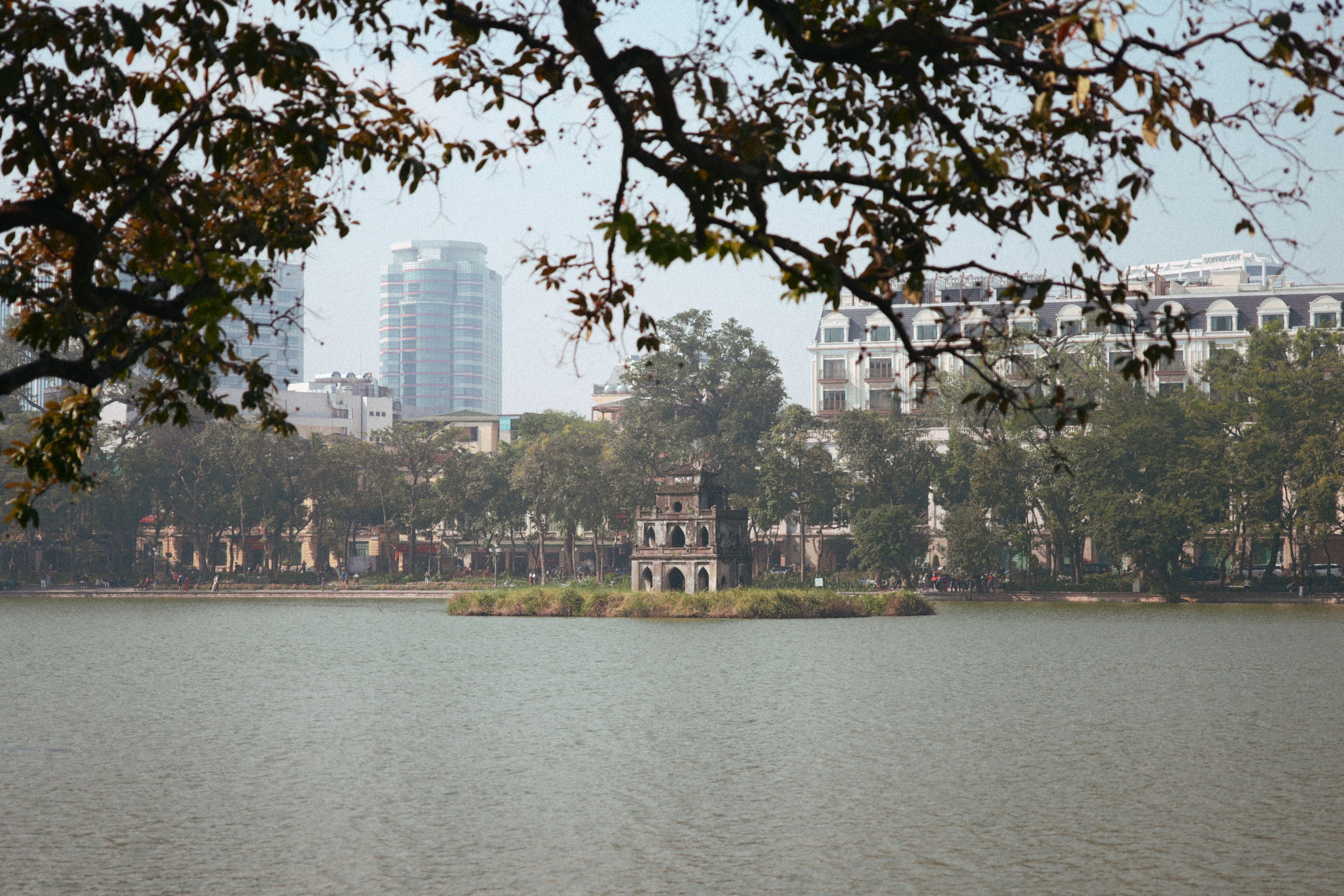 האנוי: Peaceful view of Hoan Kiem Lake with Turtle Tower in Hanoi, Vietnam with city skyline.