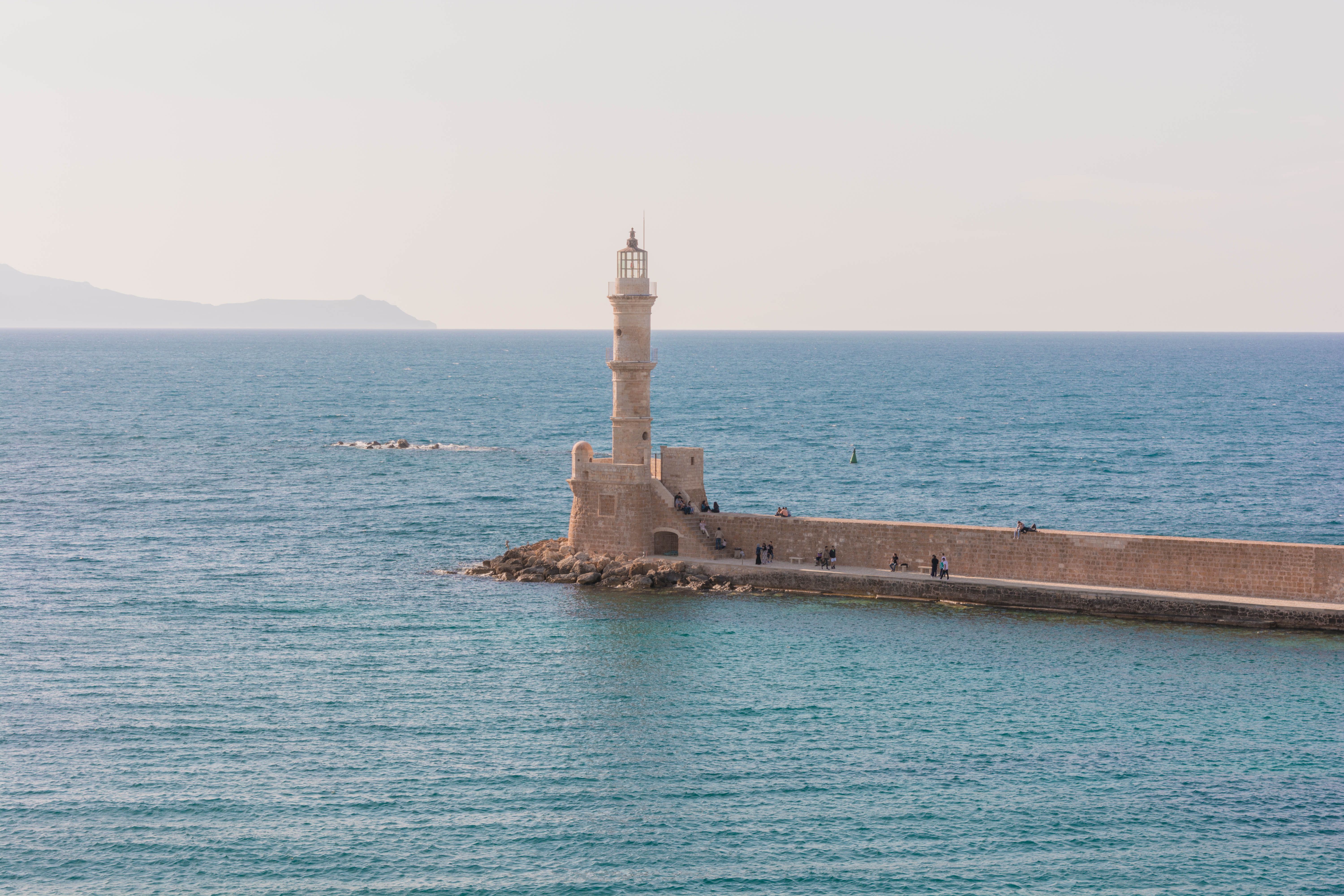 חאניה: Chania's iconic lighthouse standing in a serene Mediterranean sea, perfect for travel enthusiasts.