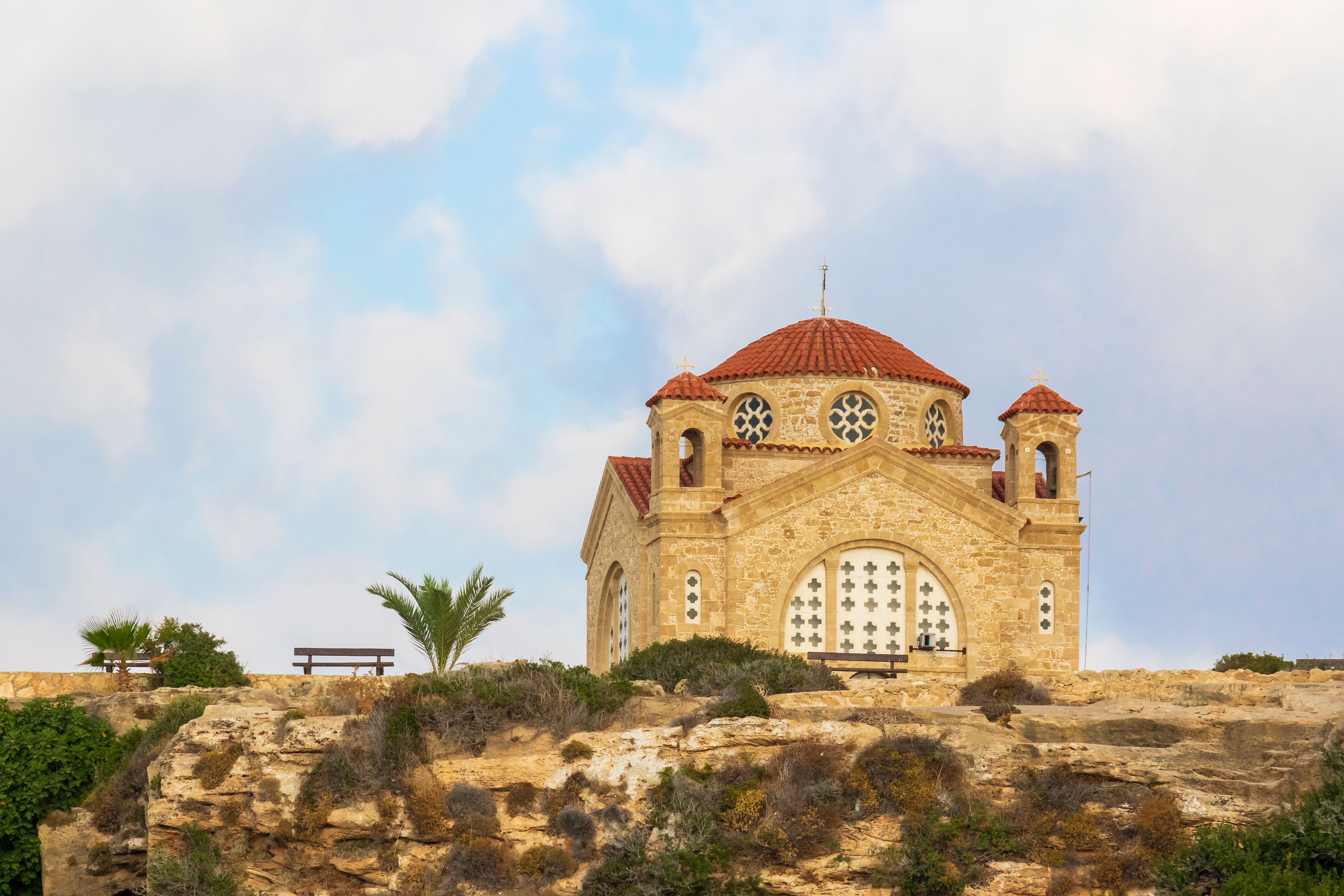 פאפוס: Scenic view of an Orthodox church on a cliff in Peyia, Paphos, Cyprus, under a cloudy sky.
