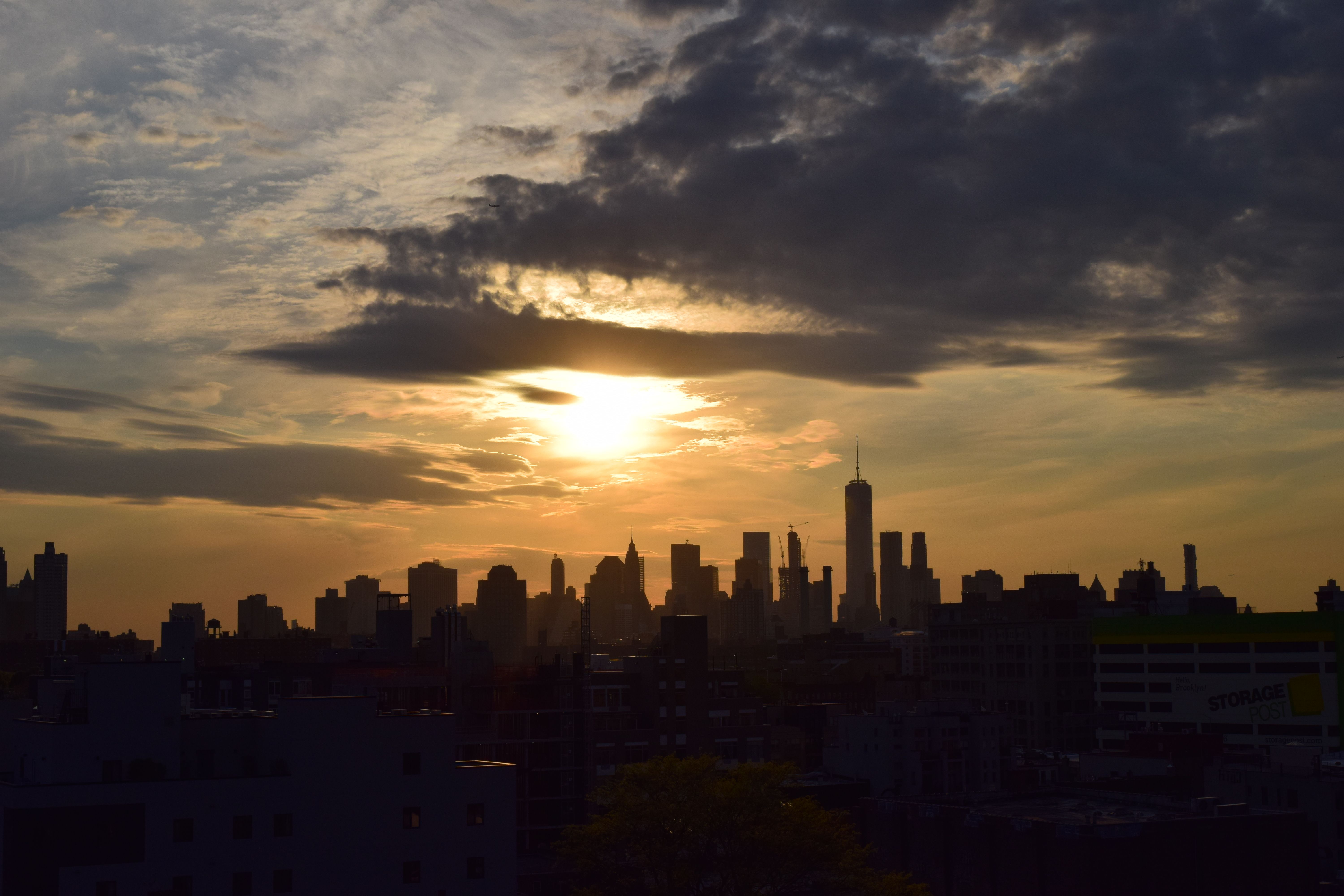 ניו יורק: Silhouette of the New York City skyline against a vibrant sunset sky.