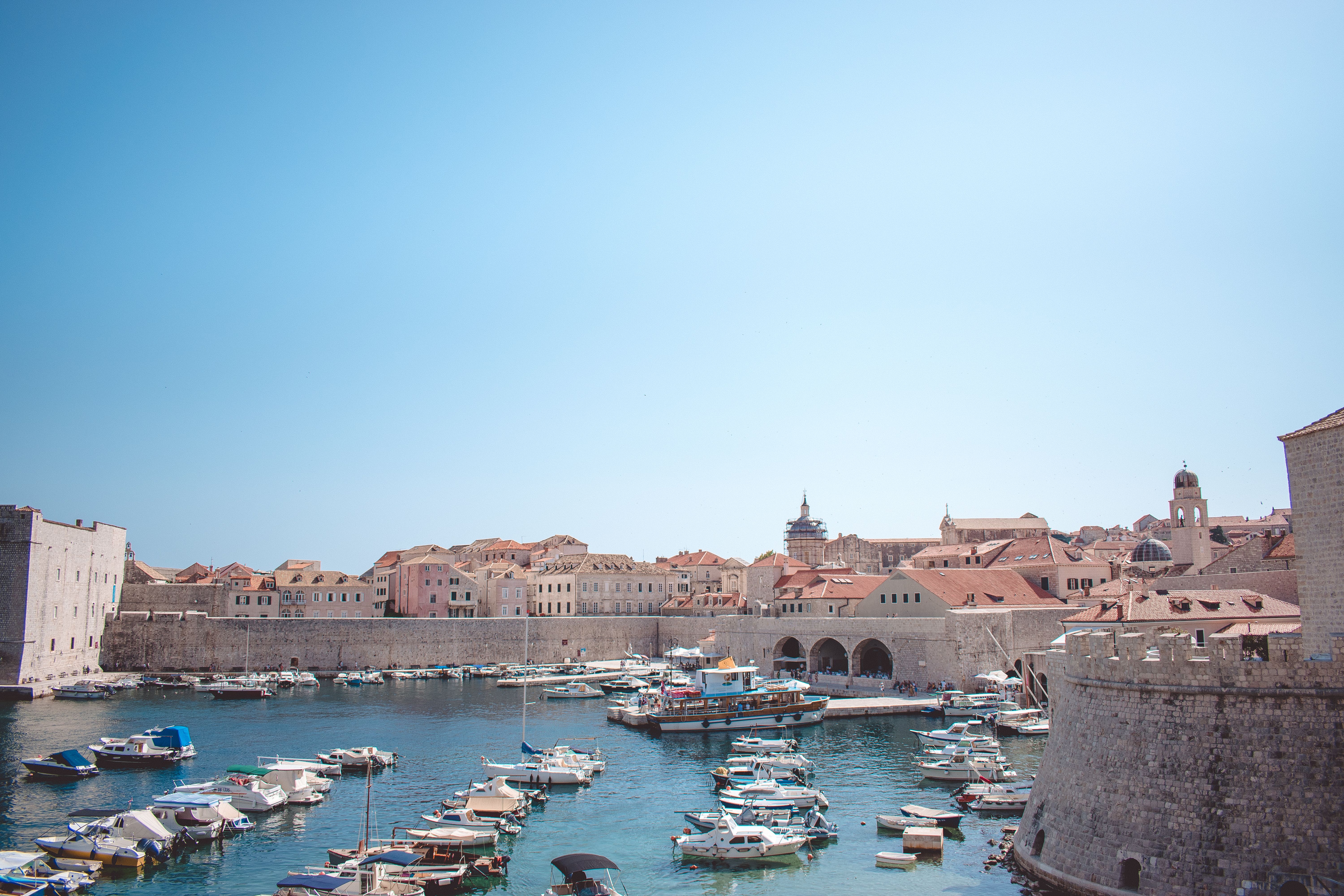 דוברובניק: Charming view of the historic harbor in Dubrovnik, Croatia, with boats and medieval architecture.